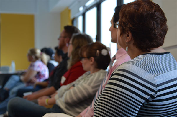 A line of sitting adult volunteers attends GLSEN's NYC Training of Trainers, or TOT. They look in the same direction and quietly listen. 